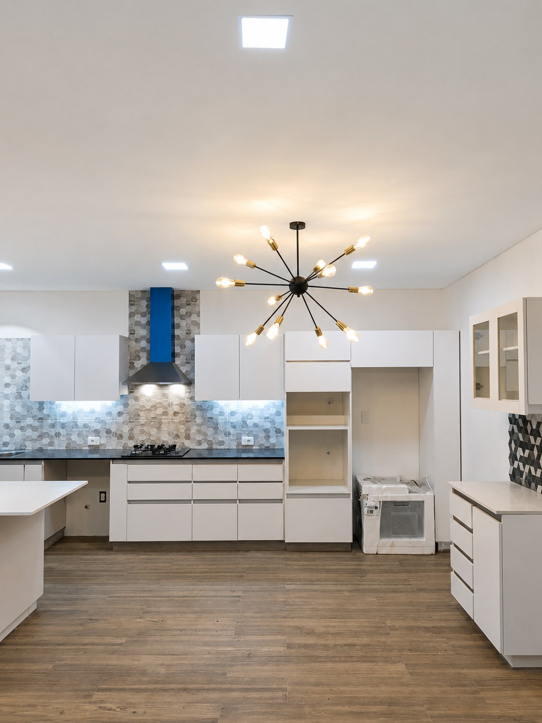 Cocina amplia terminada con iluminación central y mobiliario de madera