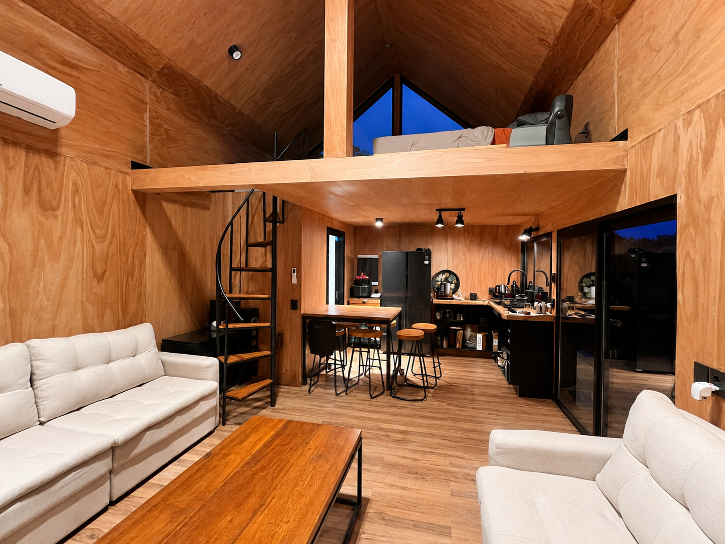 Interior de cabaña con loft, cocina integrada y revestimientos de madera