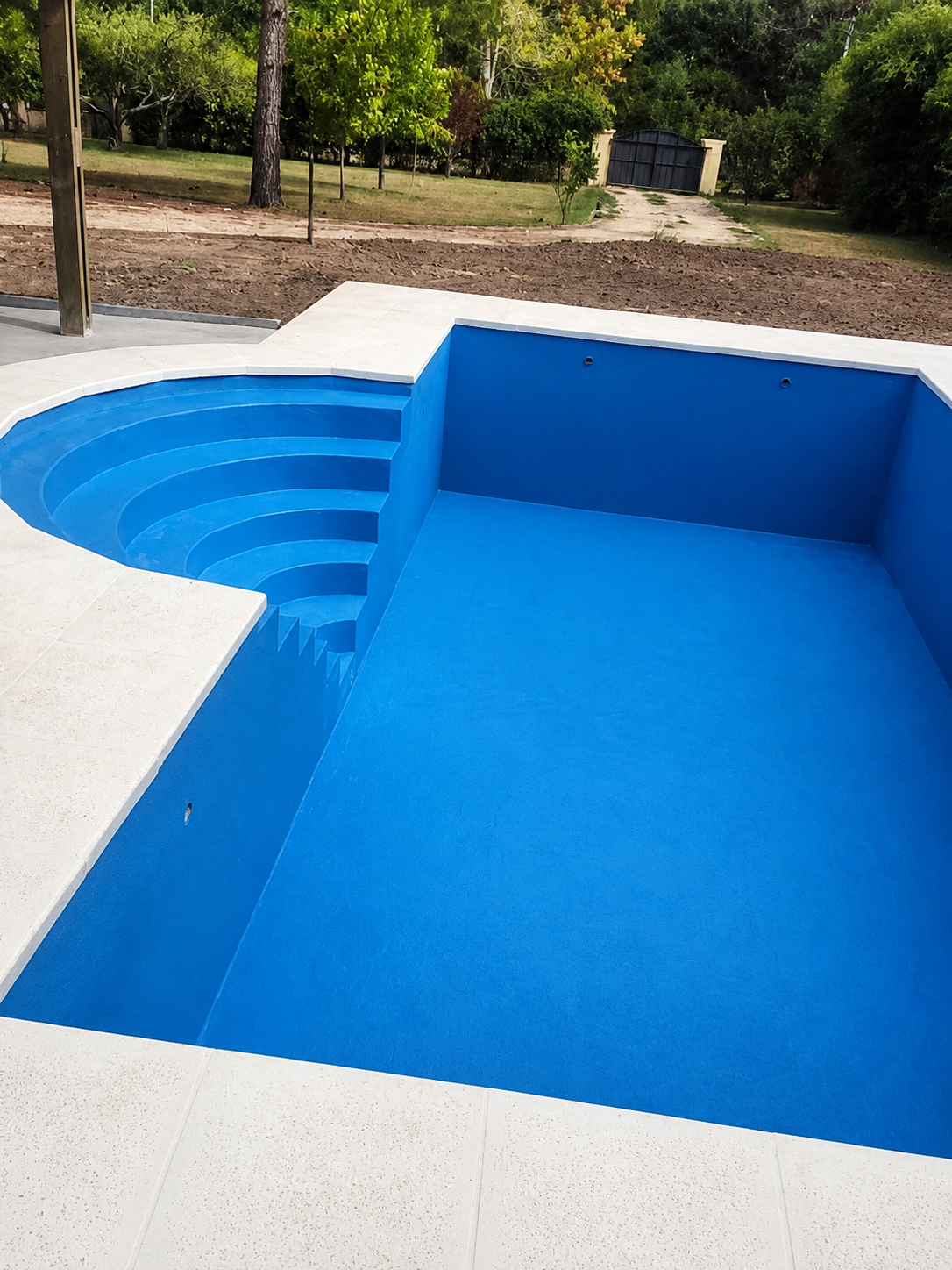 Piscina vacía en proceso con escalera curva y borde bien resuelto